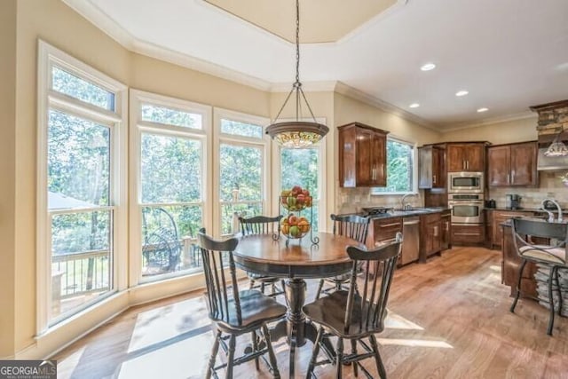 dining room with sink, crown molding, and light hardwood / wood-style floors