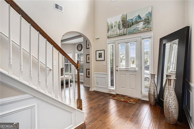 foyer entrance with dark wood-type flooring and a towering ceiling