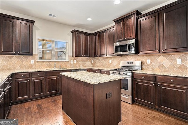 kitchen featuring sink, dark wood-type flooring, a kitchen island, and appliances with stainless steel finishes