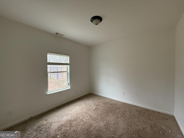 unfurnished room featuring carpet, visible vents, and baseboards