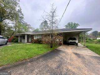 ranch-style home with a carport and a front yard