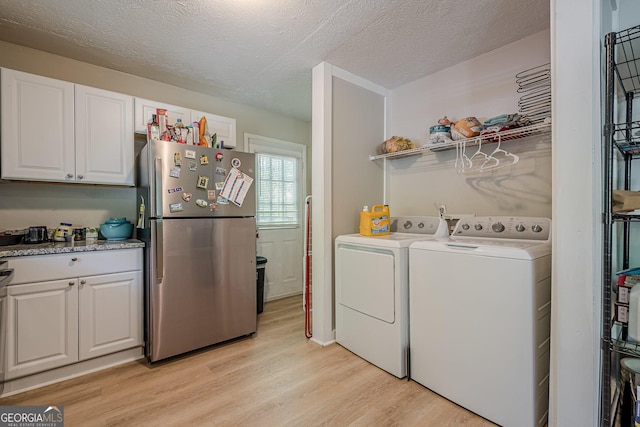 3710 Lynn Dr, Powder Springs, GA 30127 - clothes washing area featuring light wood finished floors, laundry area, washer and dryer, and a textured ceiling