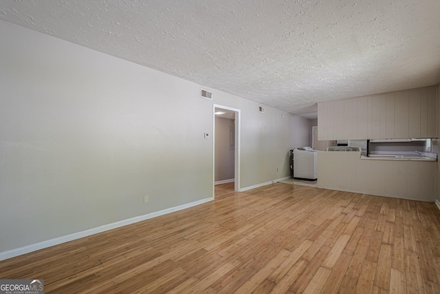 3710 Lynn Dr, Powder Springs, GA 30127 - unfurnished living room featuring a textured ceiling, light wood-type flooring, baseboards, washer / clothes dryer, and visible vents