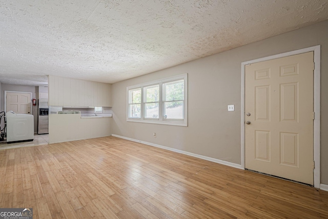 3710 Lynn Dr, Powder Springs, GA 30127 - unfurnished living room featuring light wood-type flooring, baseboards, a textured ceiling, and washer / clothes dryer