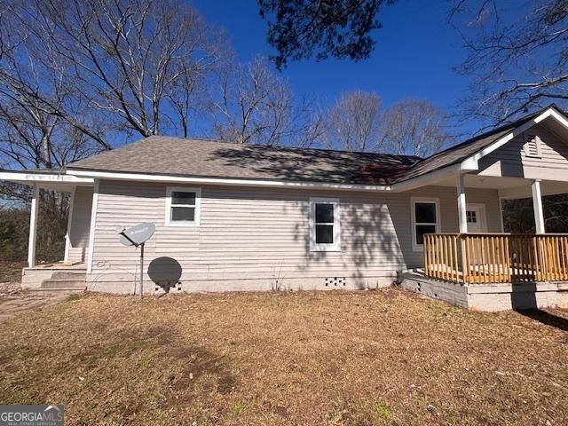 rear view of house featuring a porch and a yard