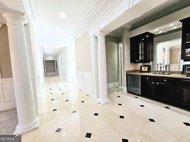 bar featuring light stone countertops, crown molding, decorative columns, and beverage cooler