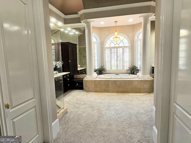 bathroom with ornate columns, ornamental molding, and tiled tub