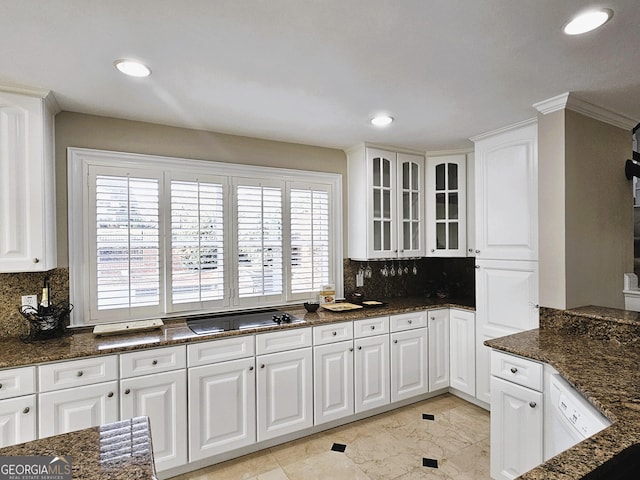 kitchen with dark stone countertops, a wealth of natural light, and white cabinets