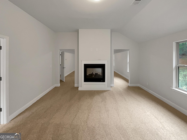 unfurnished living room with a multi sided fireplace, lofted ceiling, and light colored carpet