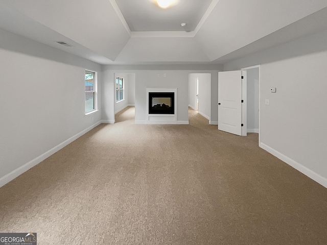 unfurnished living room featuring carpet flooring, a tray ceiling, and a multi sided fireplace