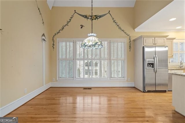 unfurnished dining area featuring a healthy amount of sunlight, a chandelier, and light wood-type flooring