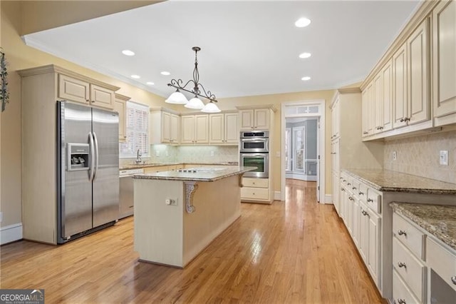 kitchen featuring a kitchen island, appliances with stainless steel finishes, a breakfast bar, decorative light fixtures, and light stone countertops