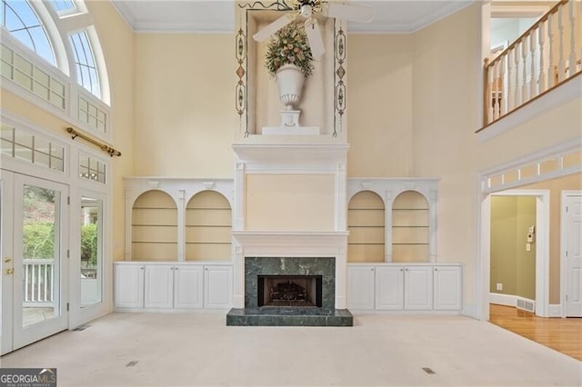 unfurnished living room with crown molding, built in shelves, and a high ceiling