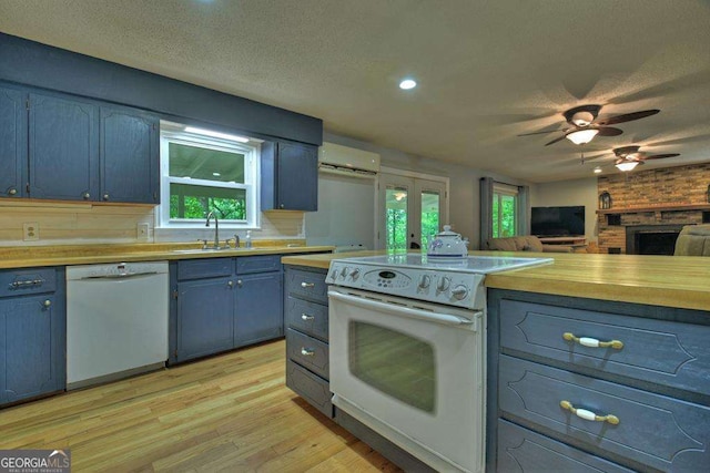 kitchen with white appliances, sink, a wall unit AC, and a textured ceiling