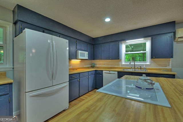 kitchen featuring sink, white appliances, light hardwood / wood-style flooring, a textured ceiling, and wood counters