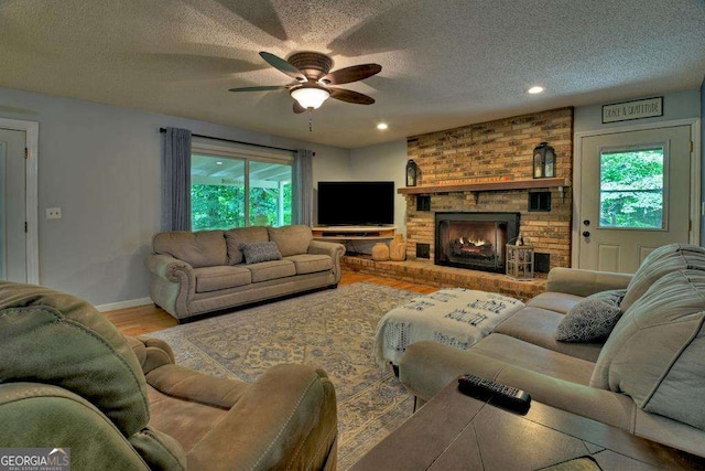 living room featuring plenty of natural light, hardwood / wood-style floors, a brick fireplace, and a textured ceiling