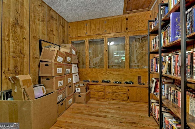 office featuring wooden walls, light hardwood / wood-style floors, and a textured ceiling