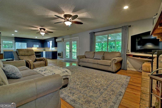 living room with french doors, ceiling fan, light hardwood / wood-style flooring, and a textured ceiling