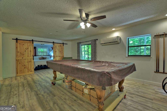 recreation room featuring hardwood / wood-style flooring, pool table, a wall mounted air conditioner, and a barn door