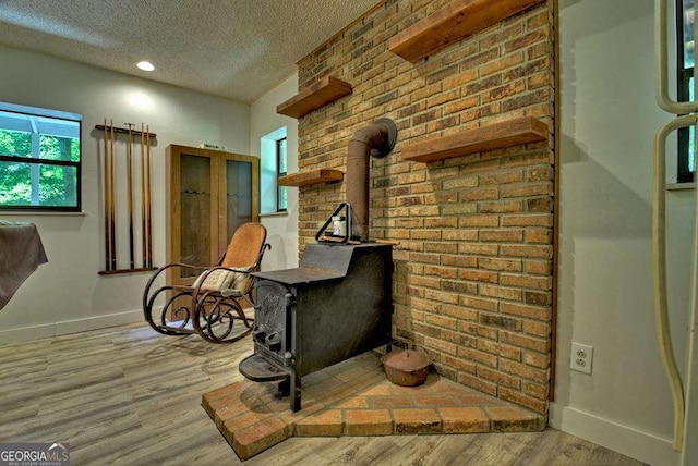 interior space featuring hardwood / wood-style floors, a textured ceiling, and a wood stove