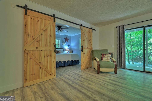 unfurnished room with wood-type flooring, a barn door, a textured ceiling, and plenty of natural light