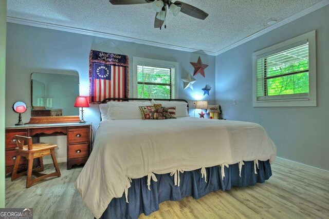 bedroom with ceiling fan, wood-type flooring, ornamental molding, and a textured ceiling