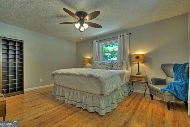 bedroom with ceiling fan, a textured ceiling, and light hardwood / wood-style flooring