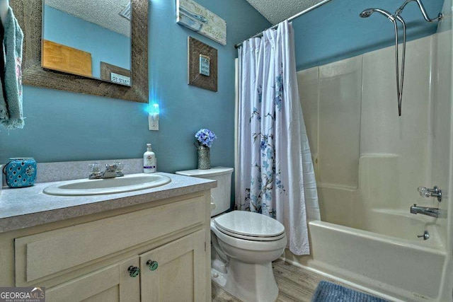 full bathroom featuring shower / bathtub combination with curtain, hardwood / wood-style floors, vanity, a textured ceiling, and toilet