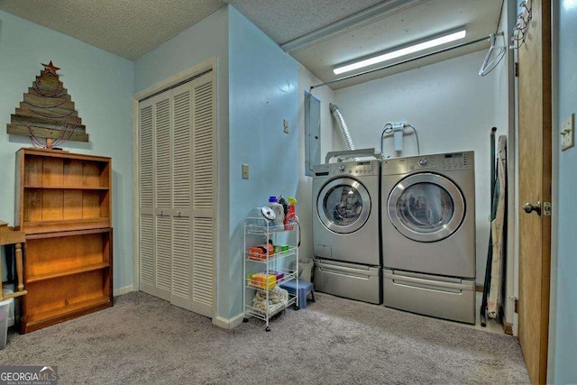 clothes washing area featuring washing machine and clothes dryer, light carpet, and a textured ceiling