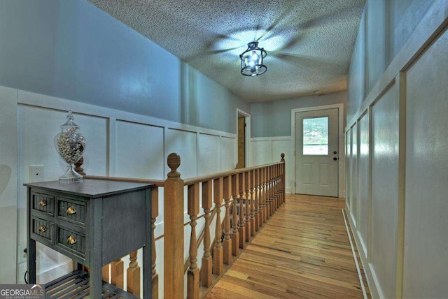 corridor with light hardwood / wood-style floors and a textured ceiling