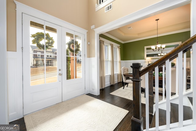 foyer featuring french doors, an inviting chandelier, crown molding, a tray ceiling, and dark hardwood / wood-style flooring