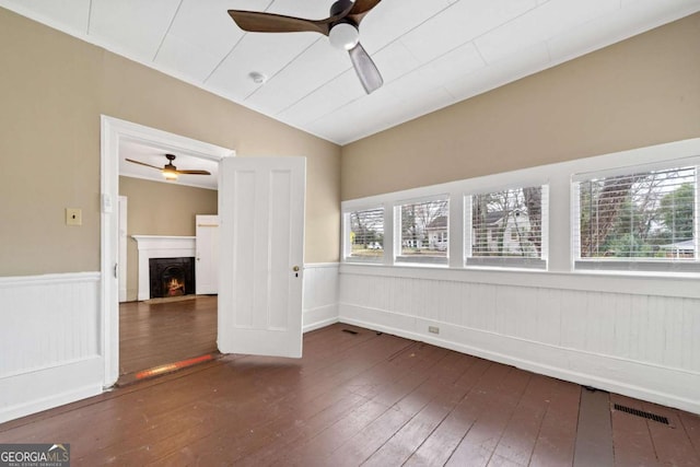 empty room featuring dark wood-type flooring, vaulted ceiling, and ceiling fan