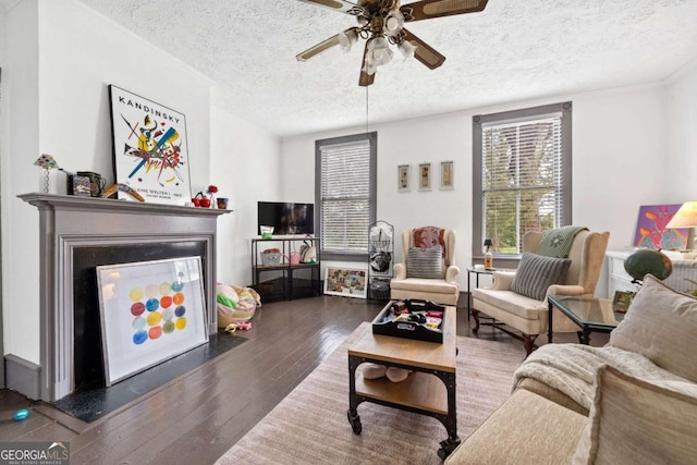 living room featuring ceiling fan, dark wood-type flooring, and a textured ceiling