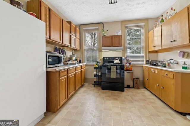 kitchen featuring white refrigerator, a textured ceiling, and electric range