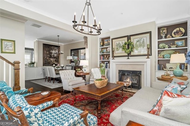 122 Brighton Blvd, Woodstock, GA 30188 - living room with crown molding, a glass covered fireplace, visible vents, a notable chandelier, and built in shelves