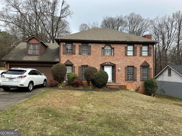 colonial inspired home with a garage and a front lawn