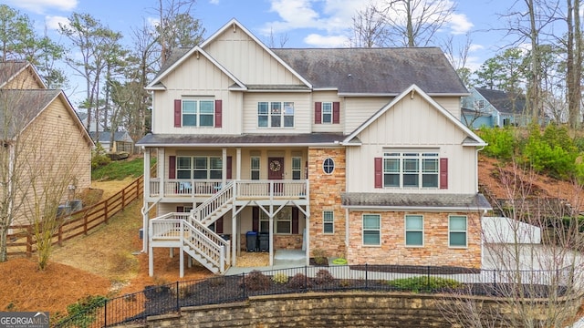 view of front facade with a porch, a fenced backyard, stone siding, stairway, and board and batten siding