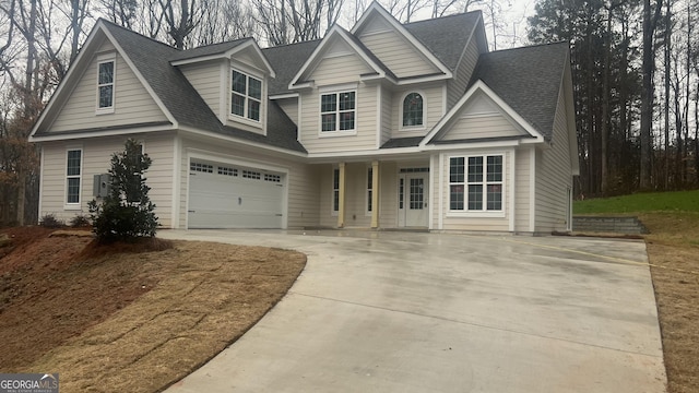 view of front of property featuring a garage, driveway, and roof with shingles