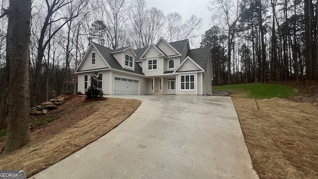 view of front of house featuring a garage, concrete driveway, and a shingled roof