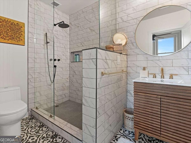 bathroom with vanity, a tile shower, tile walls, and toilet