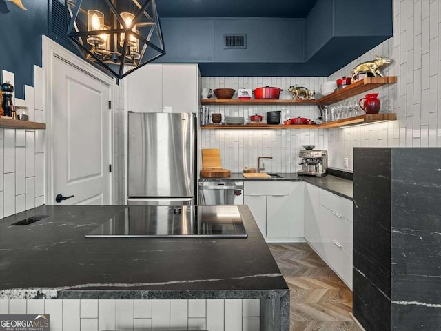 kitchen with appliances with stainless steel finishes, white cabinetry, tasteful backsplash, decorative light fixtures, and parquet flooring