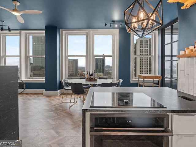 kitchen featuring ceiling fan with notable chandelier, stainless steel oven, black electric cooktop, and parquet floors