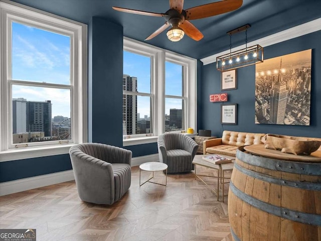 sitting room featuring light parquet flooring, ornamental molding, a wealth of natural light, and ceiling fan