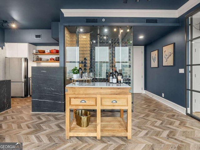 interior space featuring crown molding, stainless steel fridge, light parquet flooring, and white cabinets