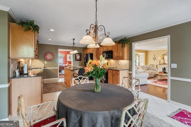 dining room featuring light tile patterned floors, crown molding, and a textured ceiling