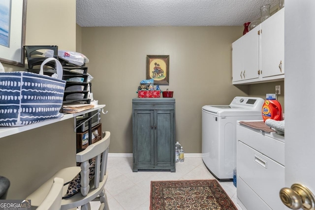 laundry area with a textured ceiling, cabinets, washer and clothes dryer, and light tile patterned floors