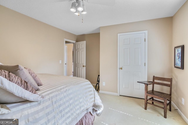 bedroom featuring a textured ceiling, light carpet, and ceiling fan