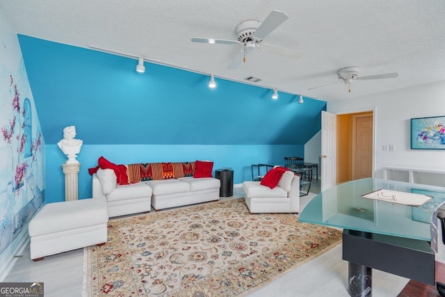 living room featuring light hardwood / wood-style flooring, lofted ceiling, rail lighting, and a textured ceiling