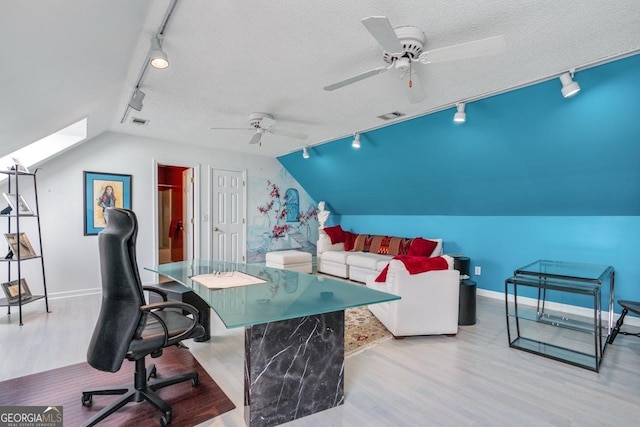 office with track lighting, a textured ceiling, light hardwood / wood-style floors, and lofted ceiling