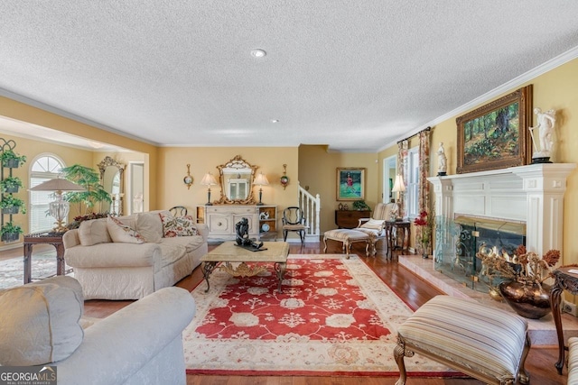 living room with hardwood / wood-style flooring, a textured ceiling, and ornamental molding